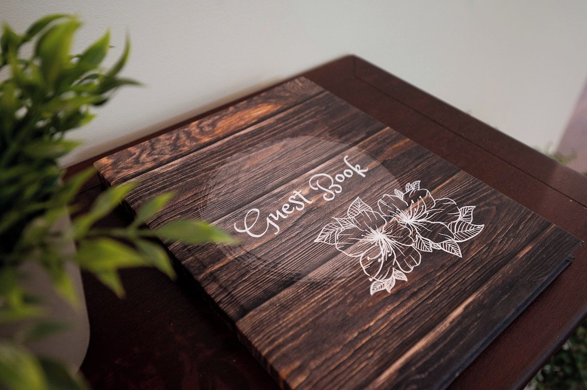 Una caja de madera con el texto 'Guest Book' y un diseño floral.