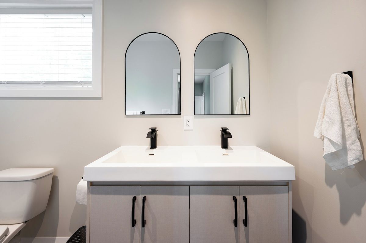 A bathroom with a white sink, two black faucets, and a mirror above.