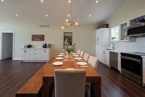 Una cocina moderna con armarios blancos, una mesa de comedor para seis personas y una lámpara colgante.