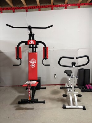 A gym with exercise equipment including a red York 401 machine, a white elliptical, and dumbbells.