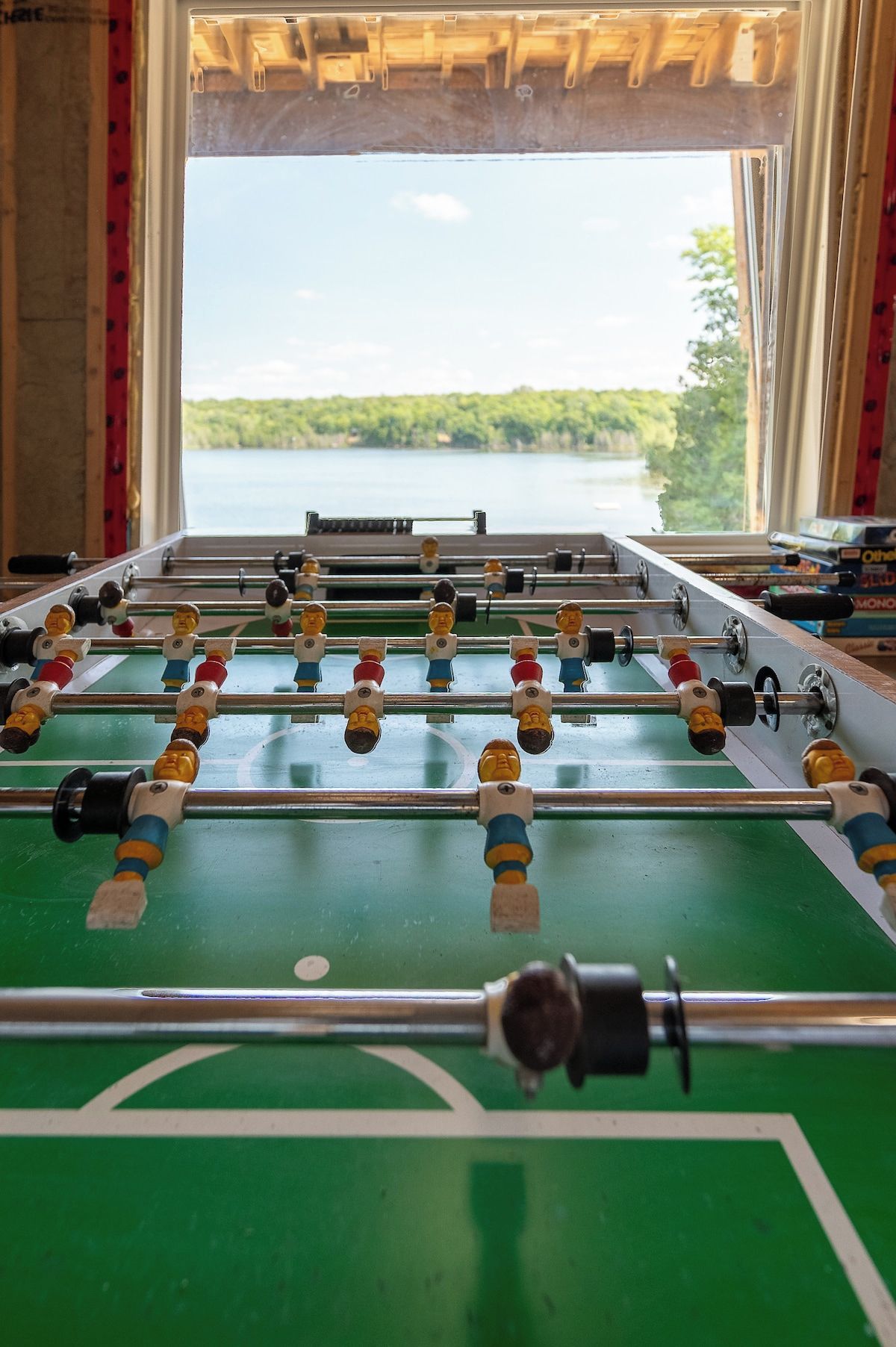 A foosball table with a view of a lake through a window.