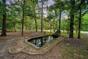 Ein friedlicher Park mit einem kleinen Teich, umgeben von Bäumen und einer Steinstruktur.