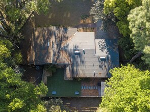 Een huis met een schuin dak, een omheinde tuin en een klein terras.