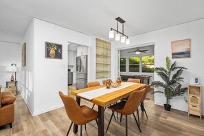 Een moderne keuken met witte kasten, een houten eettafel en een plafondventilator.