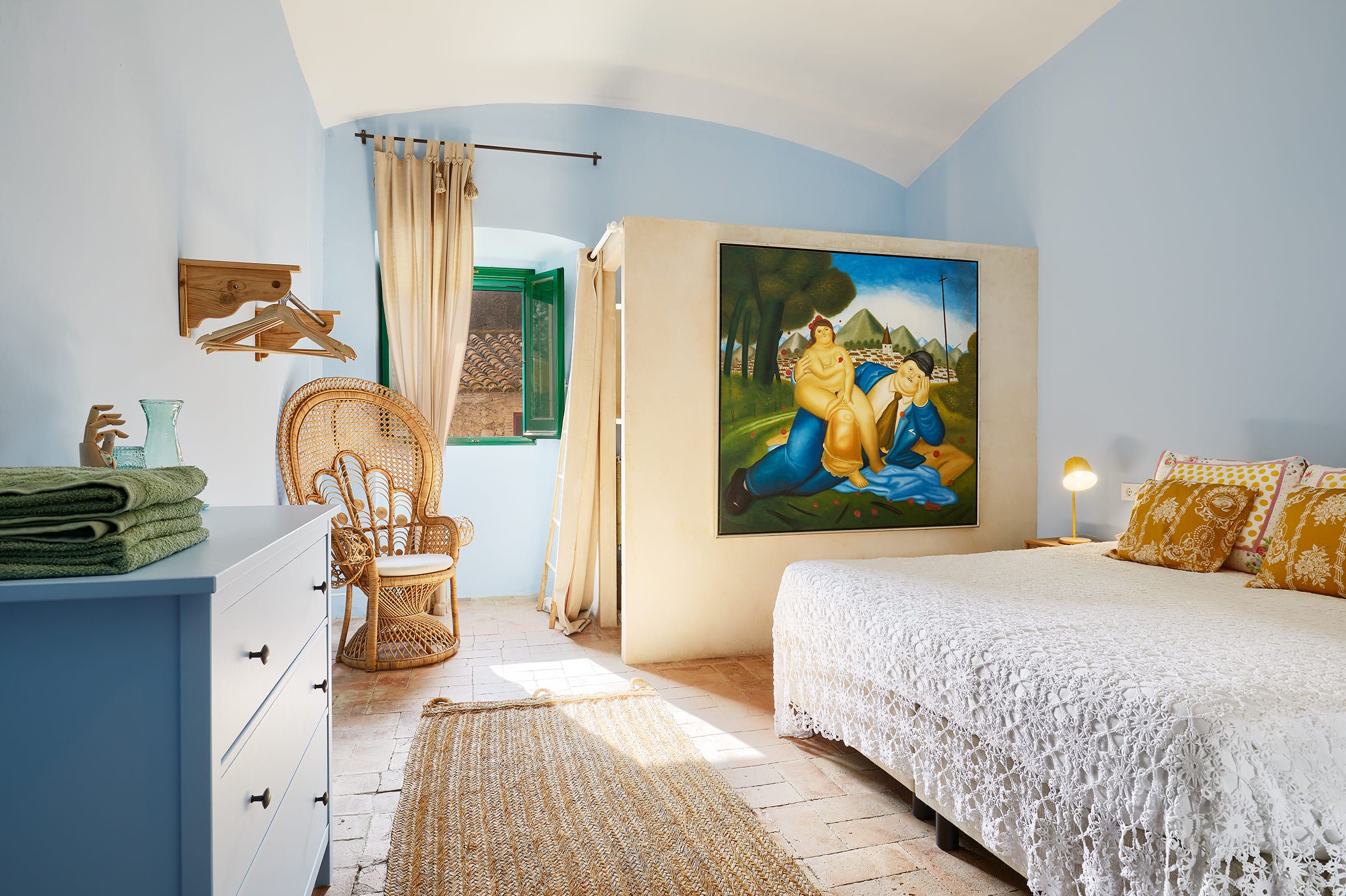 A bedroom with a bed, a chair, a dresser, a painting, and a window.