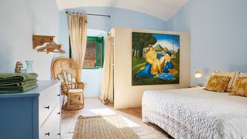 A bedroom with a bed, a chair, a dresser, a painting, and a window.