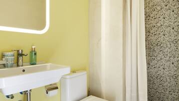 Un baño con lavamanos blanco, inodoro y cortina de ducha.