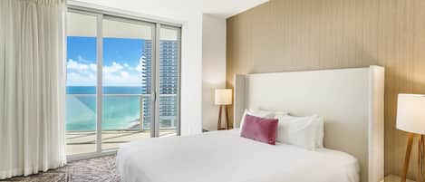 A hotel room with a large bed, a view of the ocean, and a cityscape.