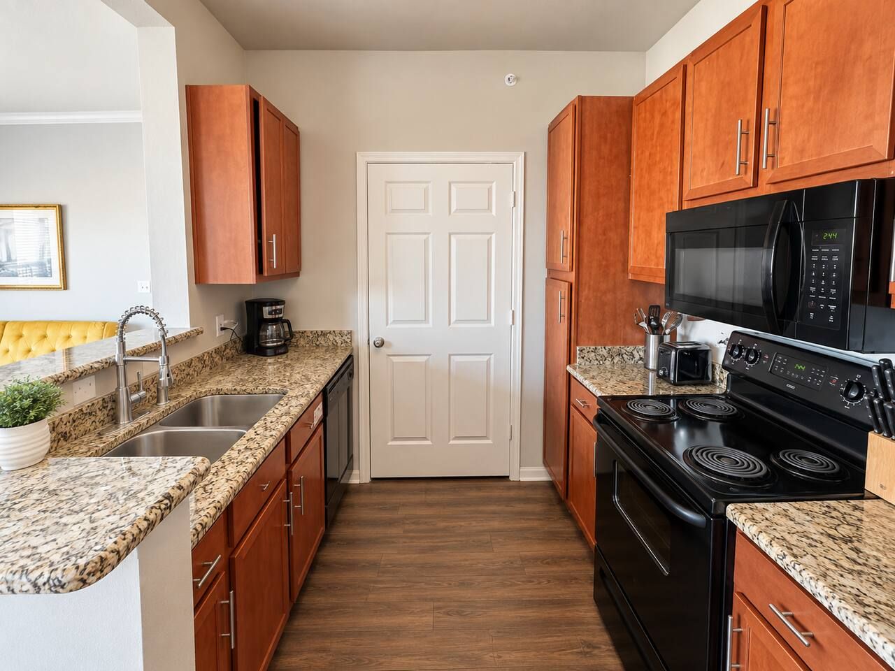 A kitchen with wooden cabinets, a black stove, a microwave, and granite countertops.