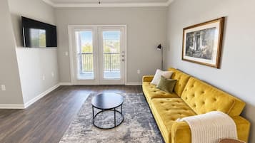 A living room with a yellow sofa, a round coffee table, and a ceiling fan.