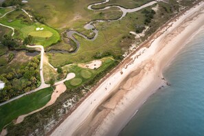 An aerial view of a coastal golf course with sand dunes, water bodies, and a beach. - The Point at Ocean point: Luxury at the Edge of Everything (Isle of Palms)
