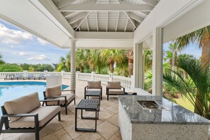 A covered outdoor seating area with a pool, lounge chairs, and a bar. - The Point at Ocean point: Luxury at the Edge of Everything (Isle of Palms)