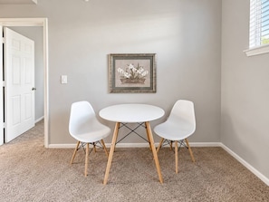 A room with a white door, a framed picture on the wall, and a round table with two white chairs. - Sleepover | Lovely 1BD/1BA + Gym - Corpus Christi (Corpus Christi)