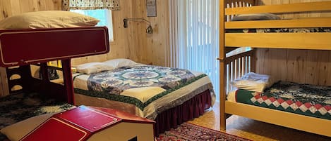 Una habitación con literas, un escritorio, un tapete estampado y paredes de madera.