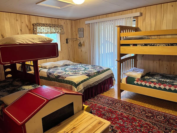 Una habitación con literas, un escritorio, un tapete estampado y paredes de madera.
