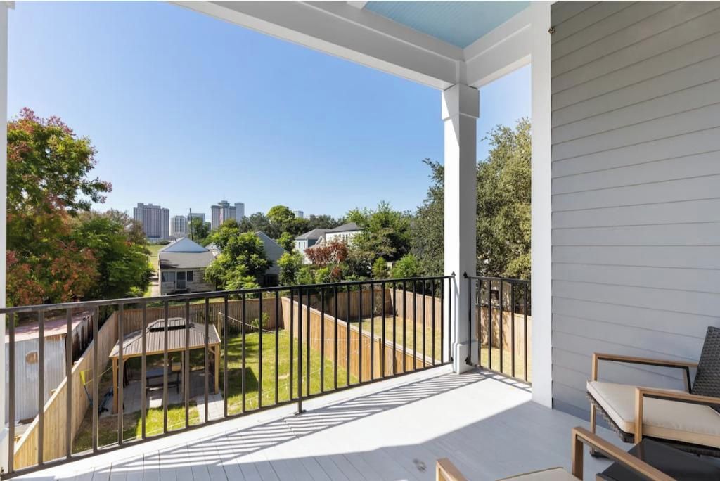 A covered balcony with a view of a backyard and neighboring houses.