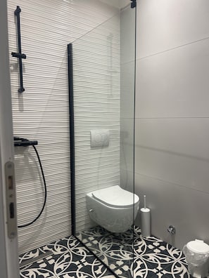 A modern bathroom with a shower, toilet, and patterned floor tiles. - Rezidenca Moderne 4R–In the Heart of Shkodër,a stylish building,central location (Shkodër)