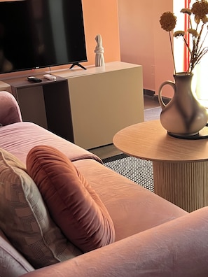 A modern living room with a sofa, a television, a small cabinet, and a vase with flowers. - Rezidenca Moderne 4R–In the Heart of Shkodër,a stylish building,central location (Shkodër)