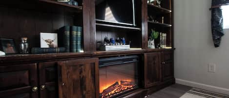 A wooden entertainment center with a fireplace, books, and decorative items.