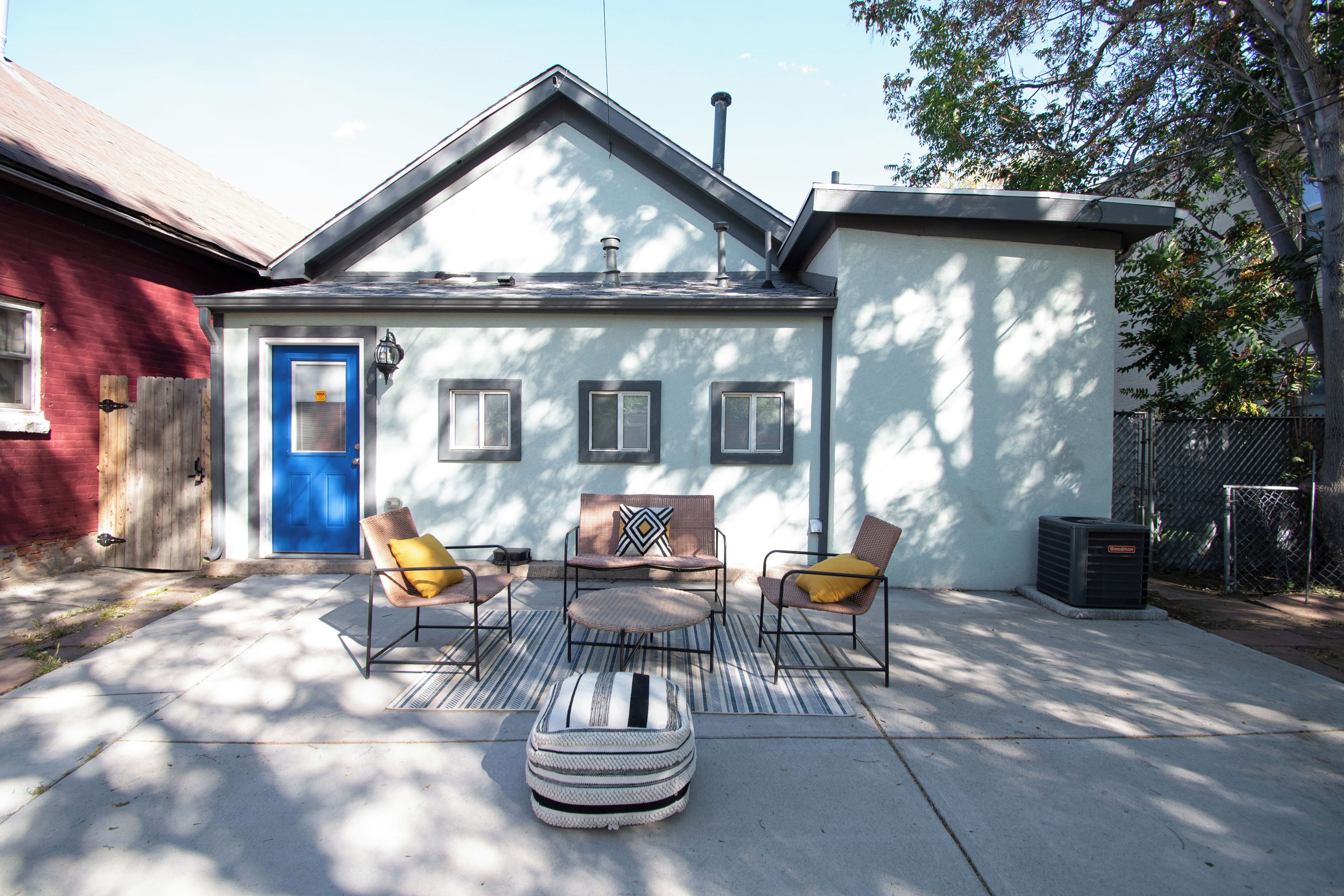 A house with a blue door, two windows, and a patio with outdoor furniture.