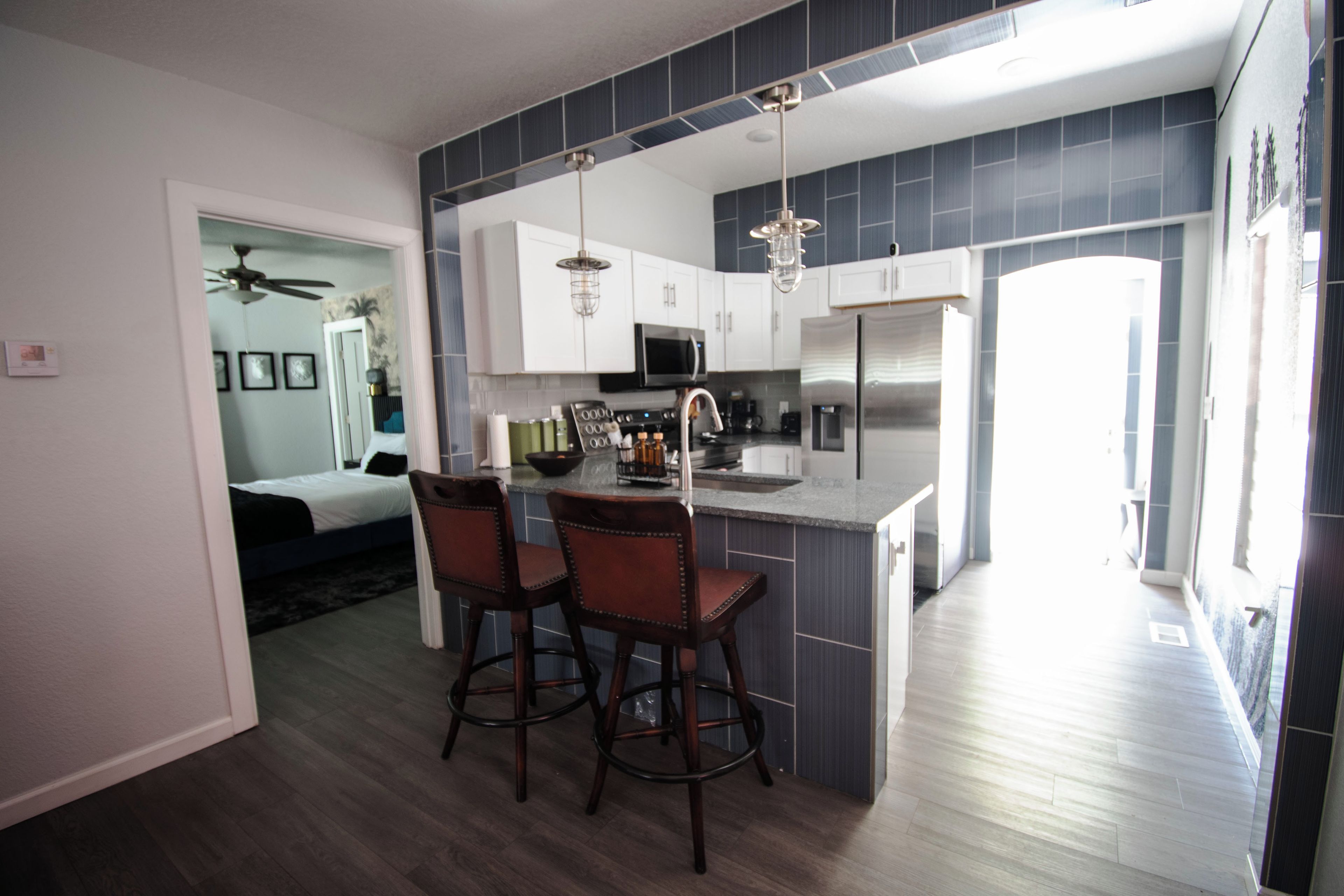 A modern kitchen with a central island, bar stools, a microwave, and a refrigerator.