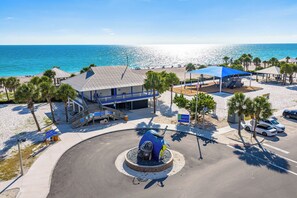 Ein Hotel direkt am Strand mit Swimmingpool, Sonnenschirmen und Blick aufs Meer.