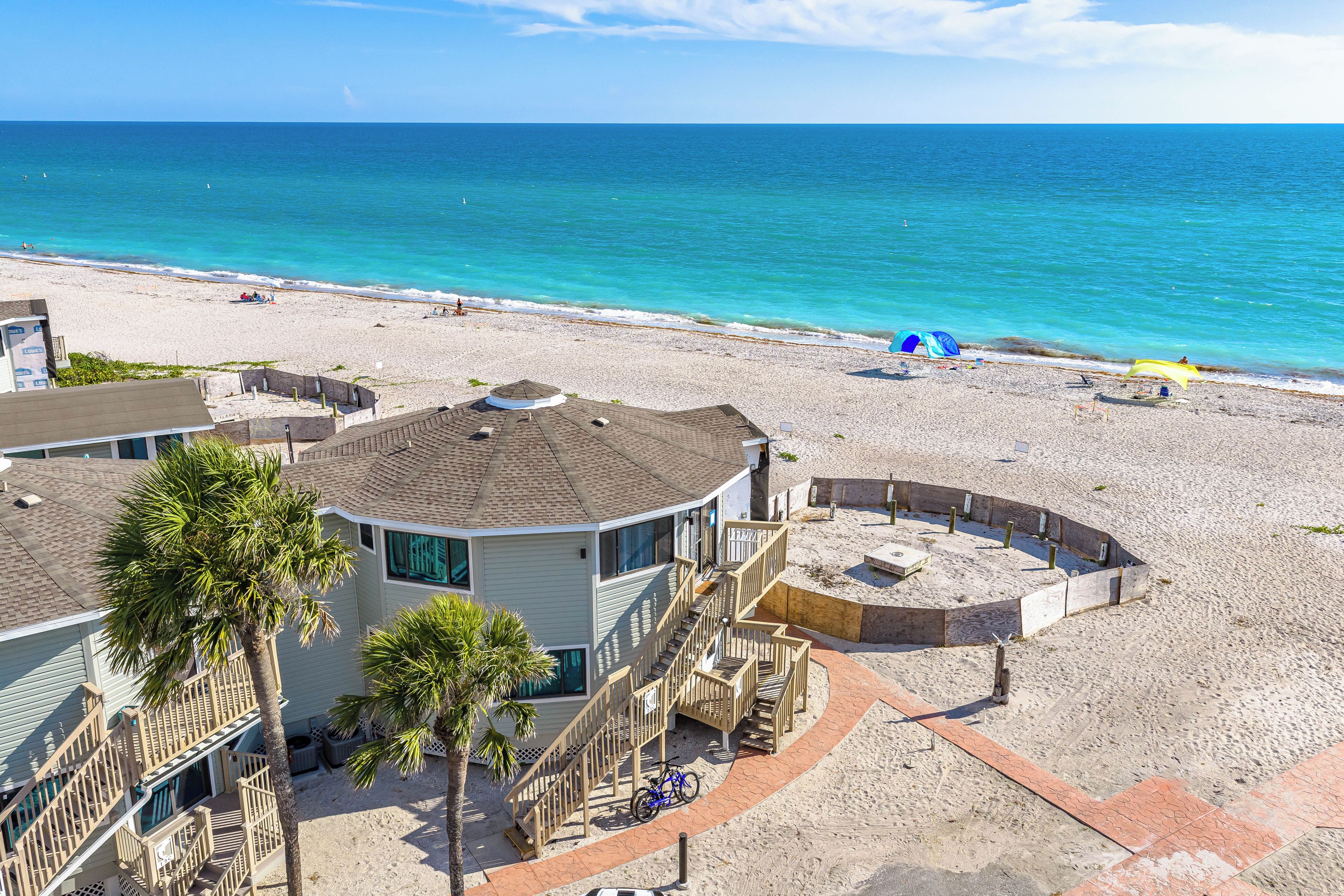 A beachfront property with a circular building, a staircase leading to a deck, and a view of the ocean.