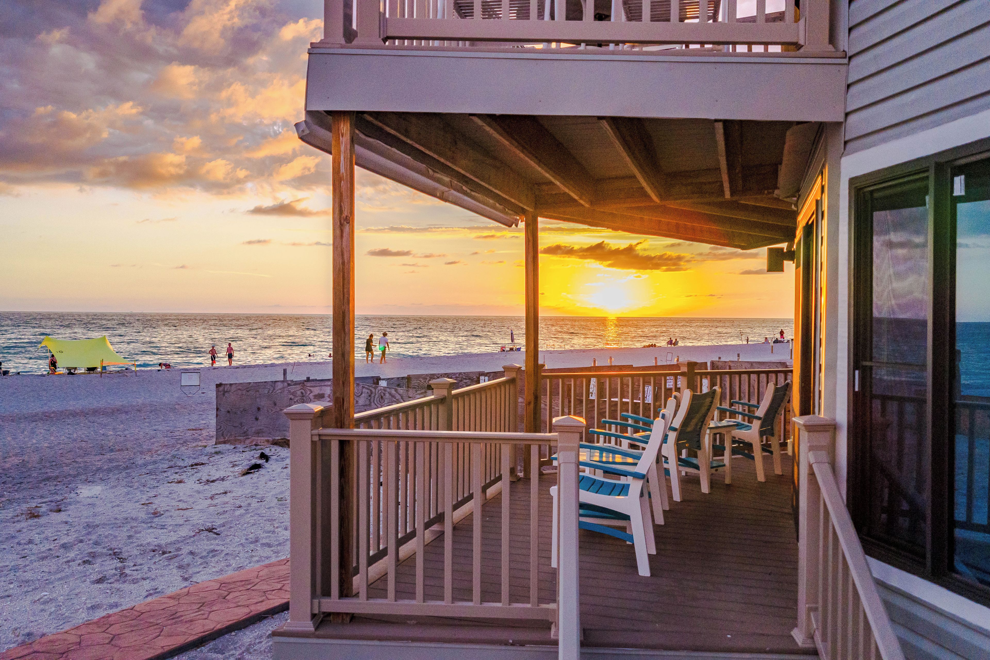 Un balcon donnant sur la plage, avec vue sur le coucher de soleil sur l’océan.
