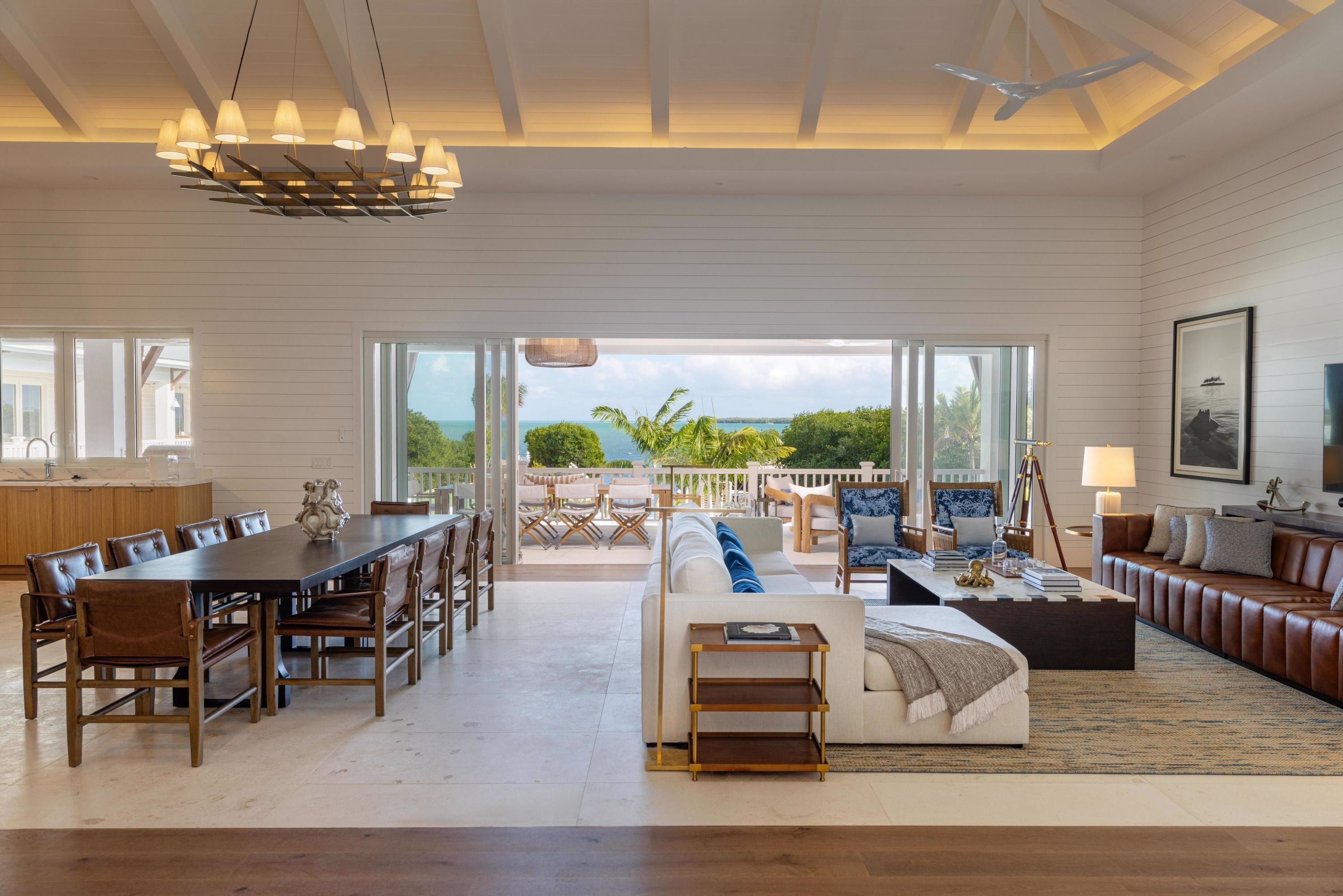 Un salón amplio con mesa de comedor, sofás y vista al océano.