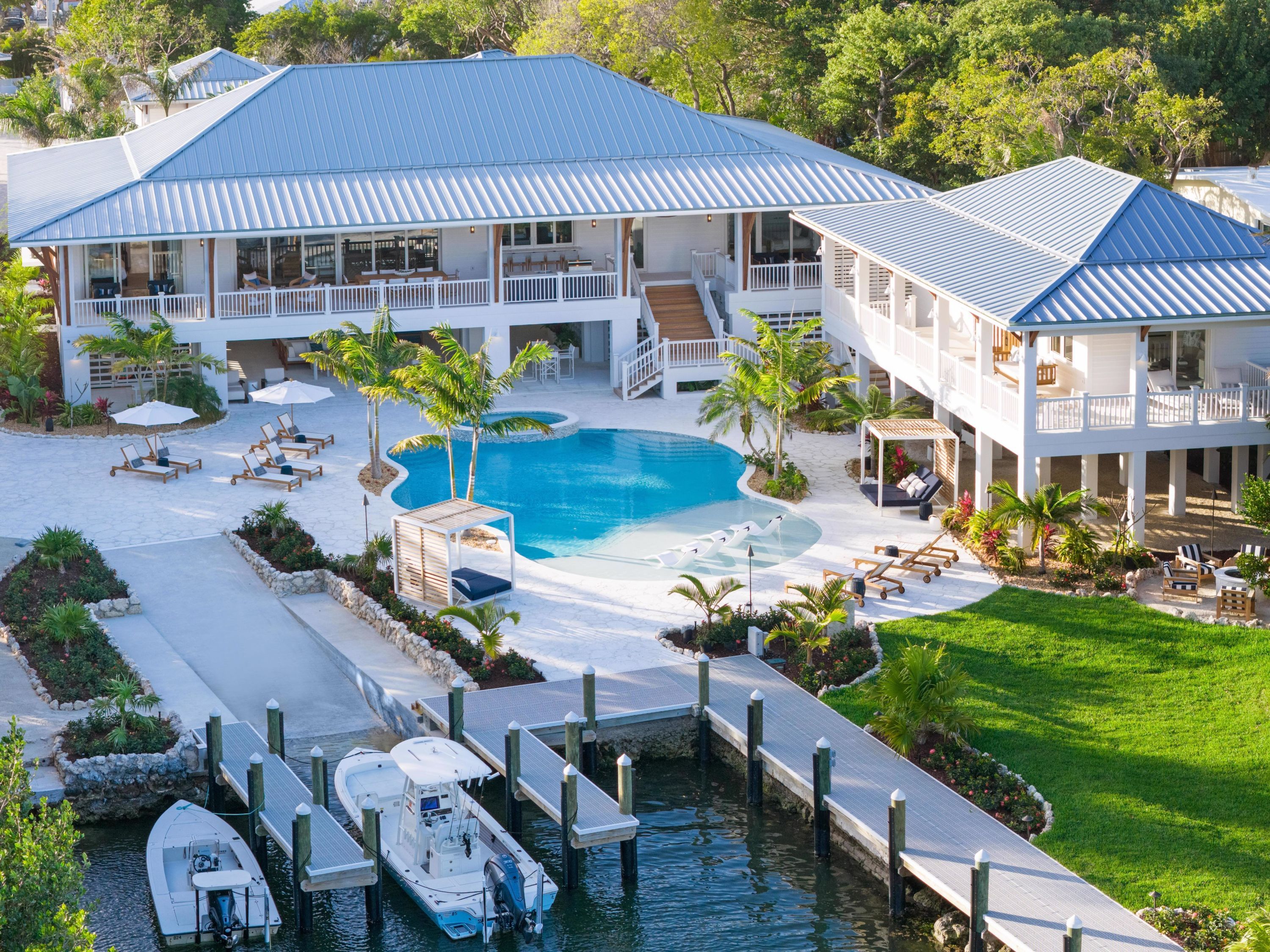 Una casa grande con piscina, barcos amarrados y un césped bien cuidado.