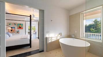 A modern bathroom with a freestanding bathtub, a large mirror, and a view of the outdoors.