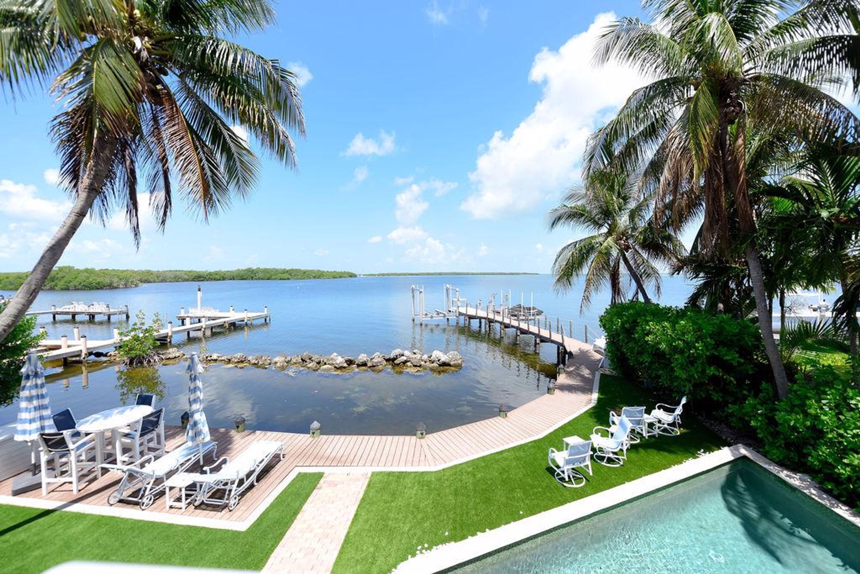 A resort pool area with lounge chairs and a view of the water.