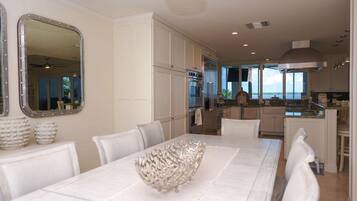 A spacious dining area with a large table, white chairs, and a decorative bowl centerpiece.
