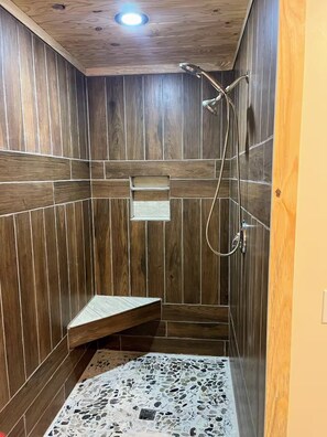 Un espace douche avec un revêtement mural en bois et un sol à motifs de galets.