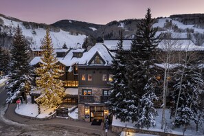 A lodge with a snow-covered roof, multiple windows, and a prominent Christmas tree with lights. - 2-Bedroom Condo at Gravity Haus (Vail)