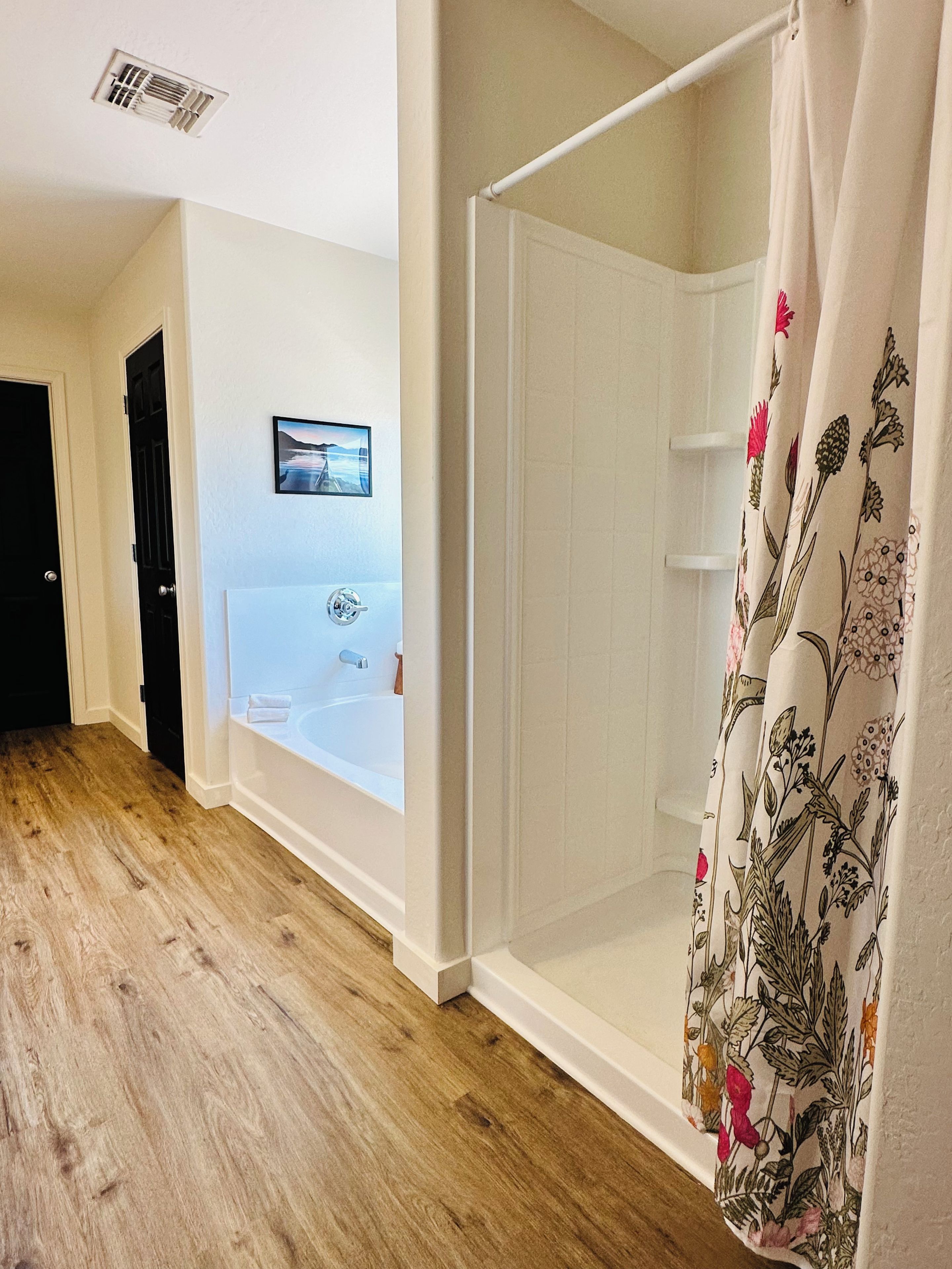 A bathroom with a bathtub, shower curtain, and wooden flooring.