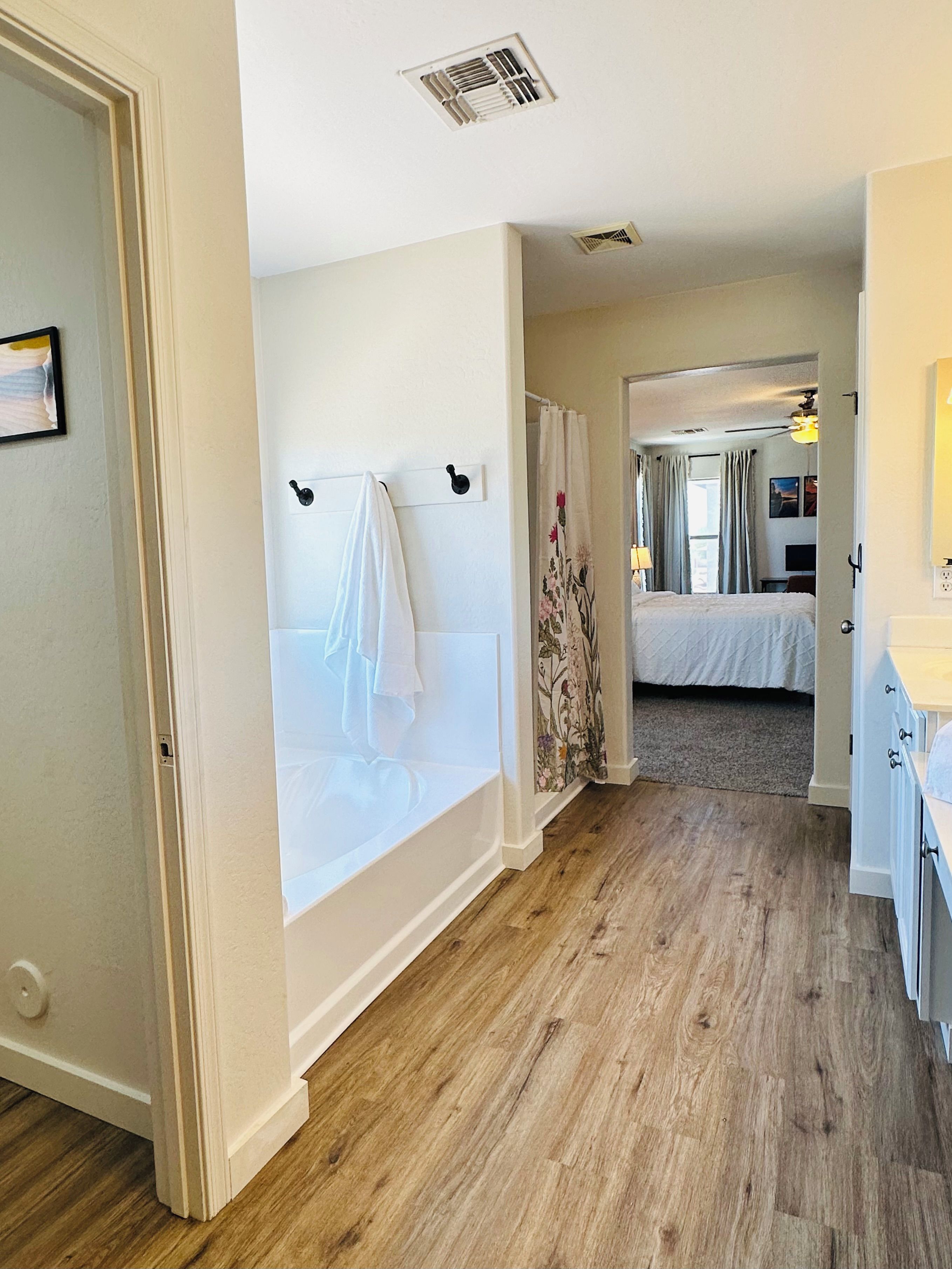 A hotel room with a bathtub, a bed, and a shower area.