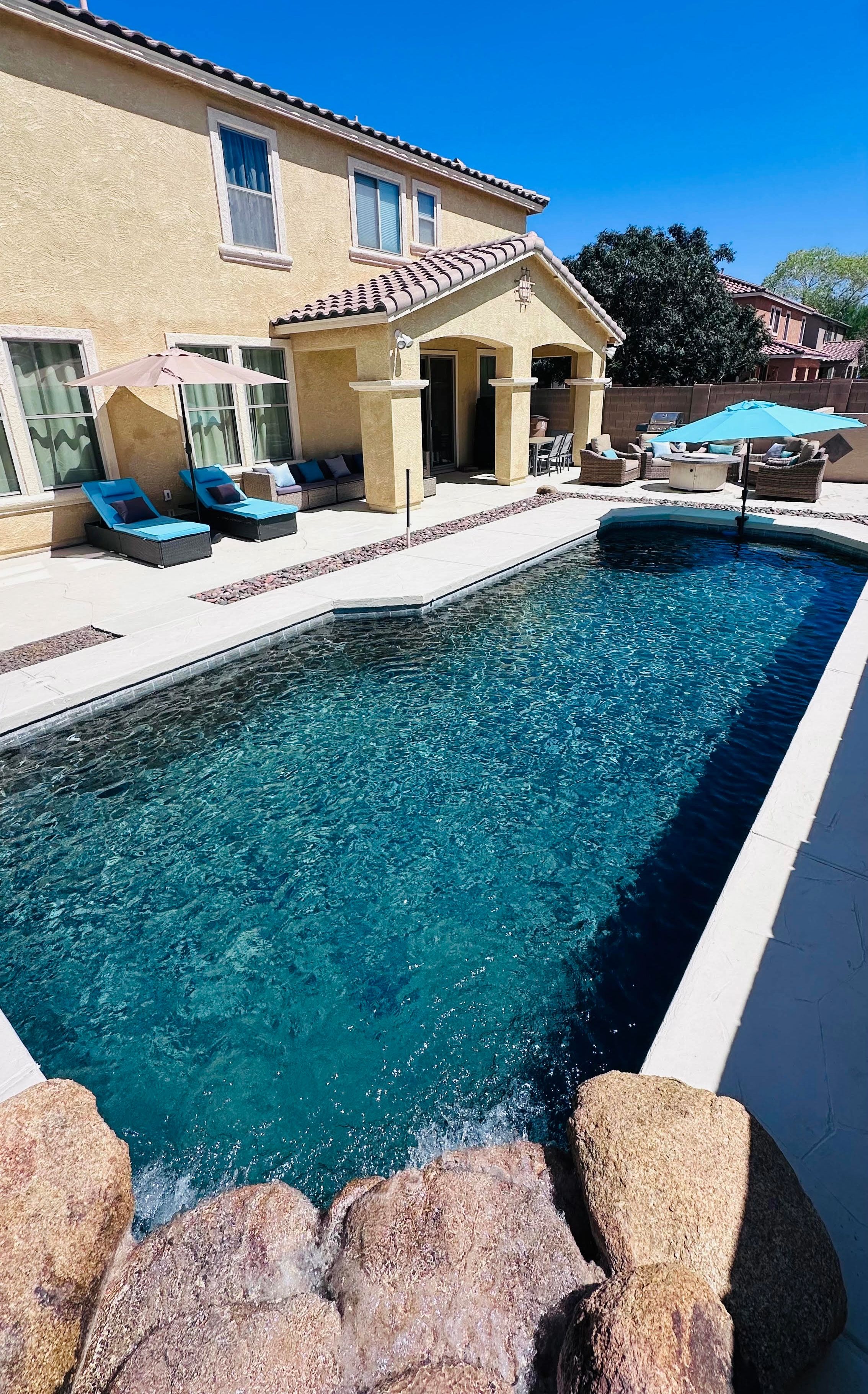 A swimming pool with lounge chairs and a patio area.