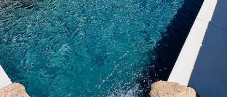 Una piscina con sillas de descanso y un área de patio.