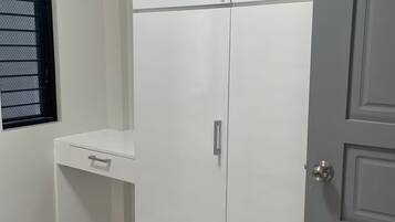 A room with a white wardrobe, a small shelf, and a door.