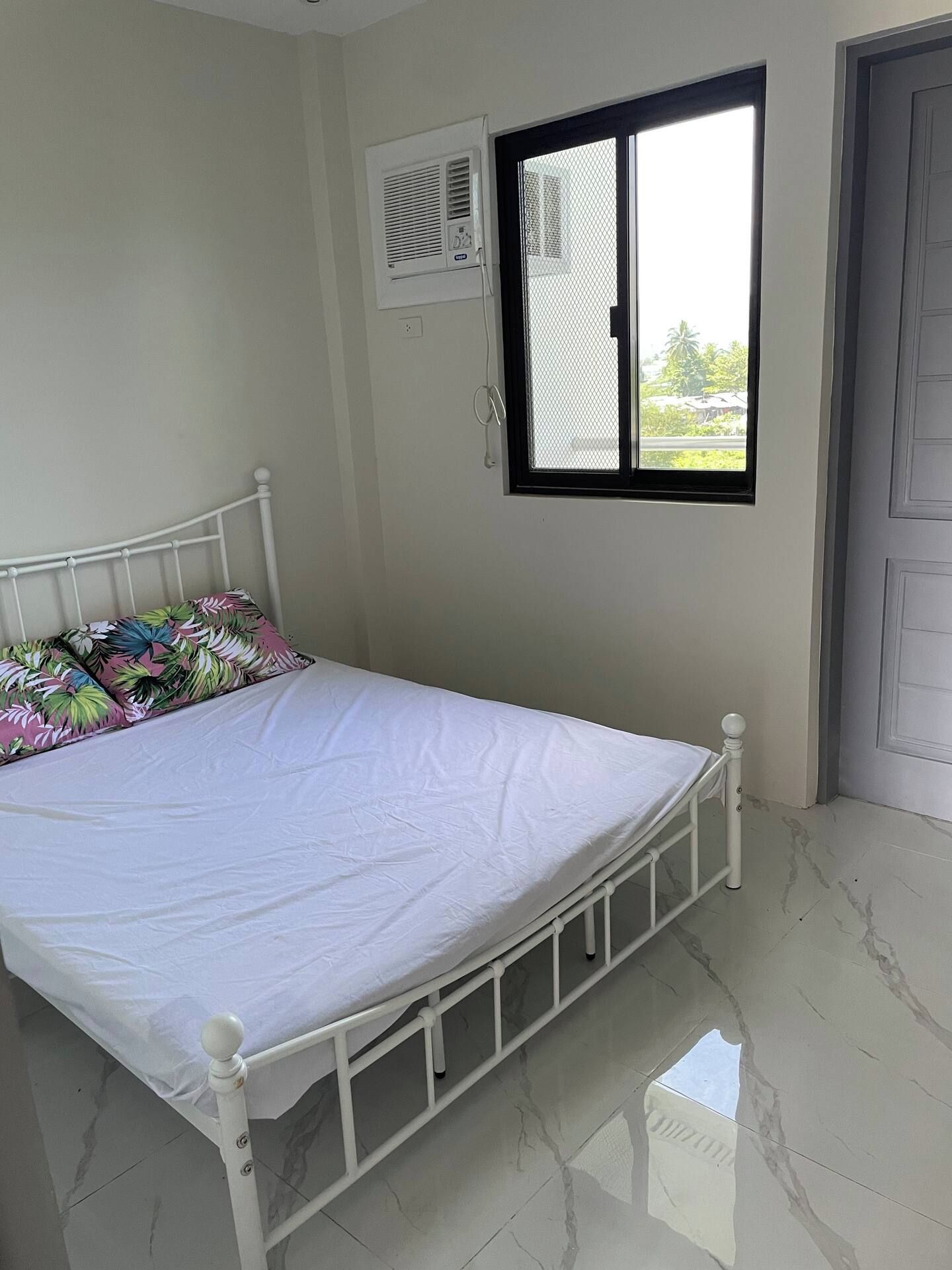 Ein Schlafzimmer mit Bett, Fenster und Tür.