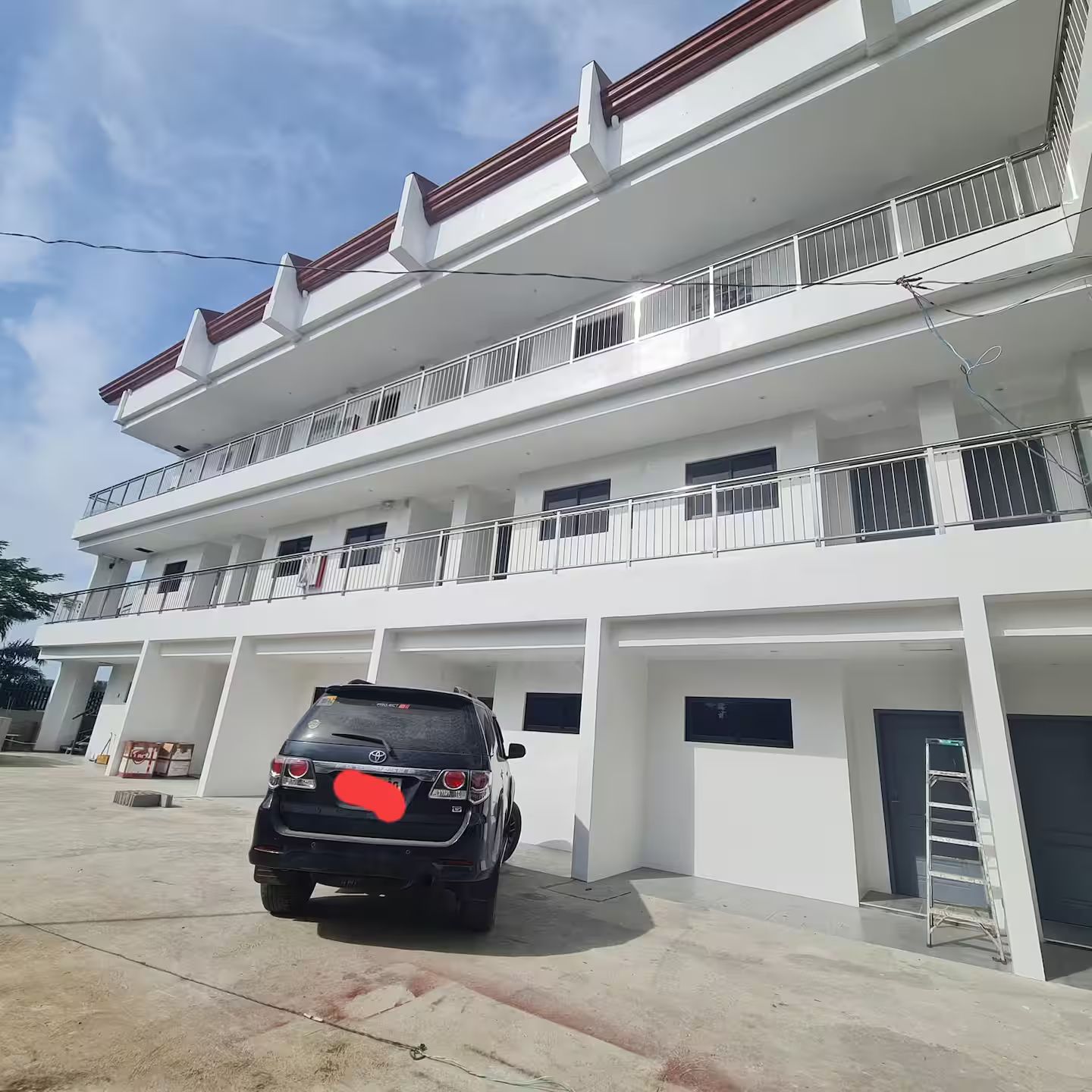 A multi-story residential building with a car parked in front.