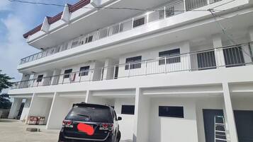 A multi-story residential building with a car parked in front.