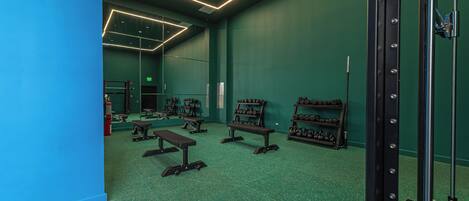 A gym with green walls, mirrored ceilings, and various exercise equipment.
