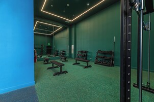 Un gimnasio con paredes verdes, techos con espejos y diverso equipo de ejercicio.