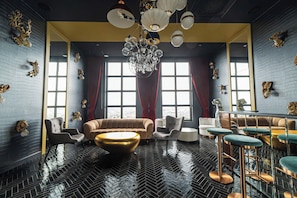 A modern interior with a herringbone floor, plush seating, a chandelier, and decorative wall mounts.