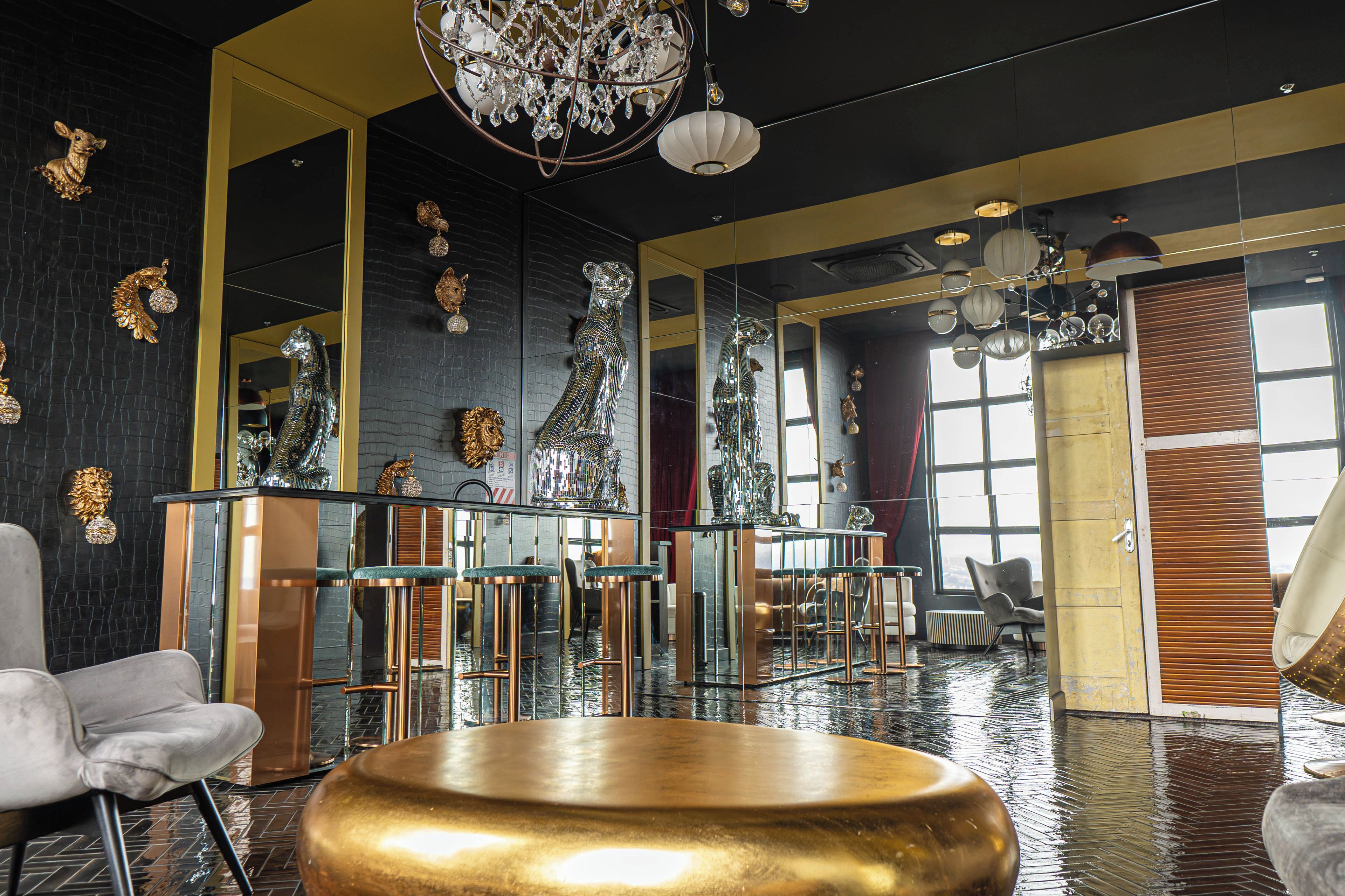 A modern interior with a reflective floor, a central gold table, and a chandelier.