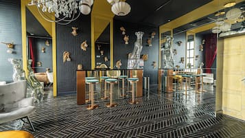 Un espace bar doté de tabourets de bar avec des revêtements miroir, d’un grand miroir et d’œuvres d’art décoratives murales.