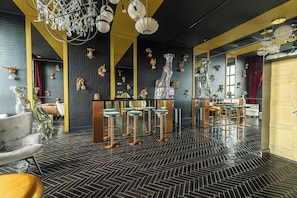 A bar area with mirrored bar stools, a large mirror, and decorative wall art.