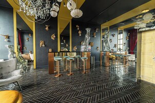Zona de bar con taburetes de barra con espejo, un espejo grande y decoración mural.